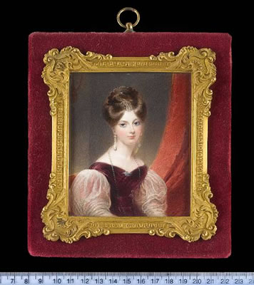 Thomas Hargreaves : A Lady, seated in a red upholstered chair, wearing plum coloured dress with puffed white gauze sleeves, seed pearl brooch in the form of a bird at her corsage, pearl necklace, pendent pearl earrings and comb in her upswept hair, red curtain beyond.